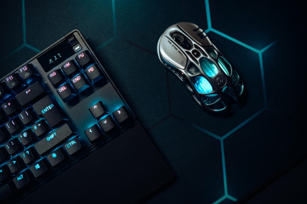 Futuristic gaming mouse and mechanical keyboard with blue LED lighting on hexagonal backdrop.